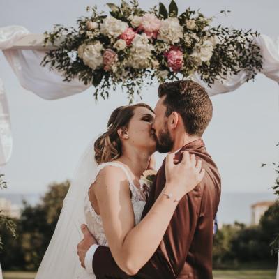 Baiser des mariés sous l'arche florale